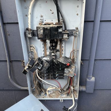 Damaged electrical panel with loose wiring.