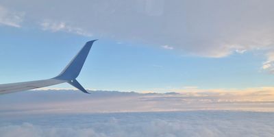 View of an airplane wing above clouds during a serene sunset.