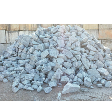 Pile of grey construction stones against a brick wall.