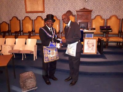 Two men in formal attire shaking hands in a ceremonial room.