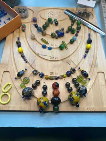 Colorful beads arranged on a wooden jewelry board for necklace making.