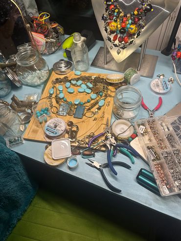 Jewelry-making workspace with beads, tools, and necklaces in progress.