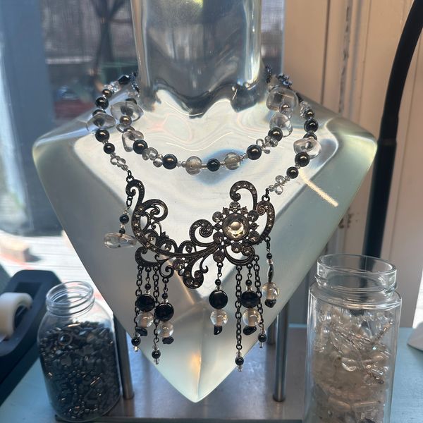 Intricate black and clear beaded necklace on frosted display bust.