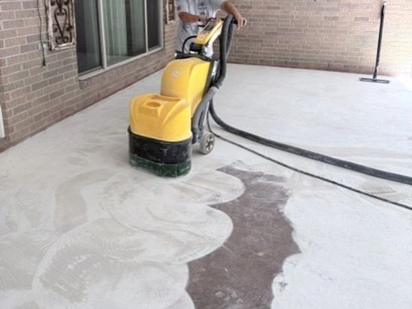 Person using yellow floor cleaning machine on concrete surface.