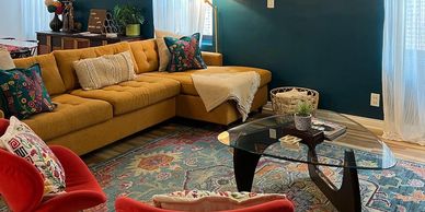A picture of a living room with a couch, area carpet. and vibrant accented decor.