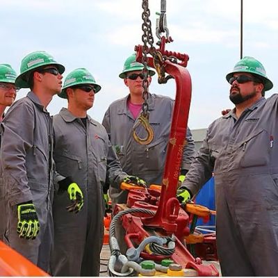 Workers in helmets inspecting heavy equipment on site.