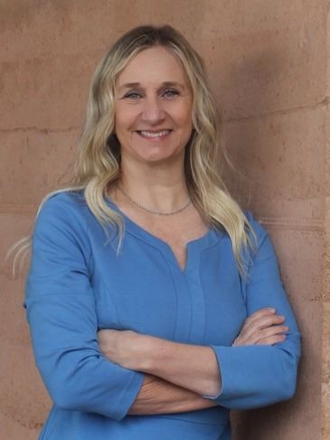 Smiling woman in blue shirt with arms crossed
