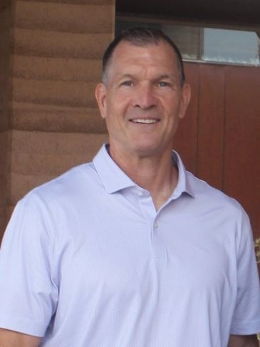 Man in a light purple polo shirt smiling.