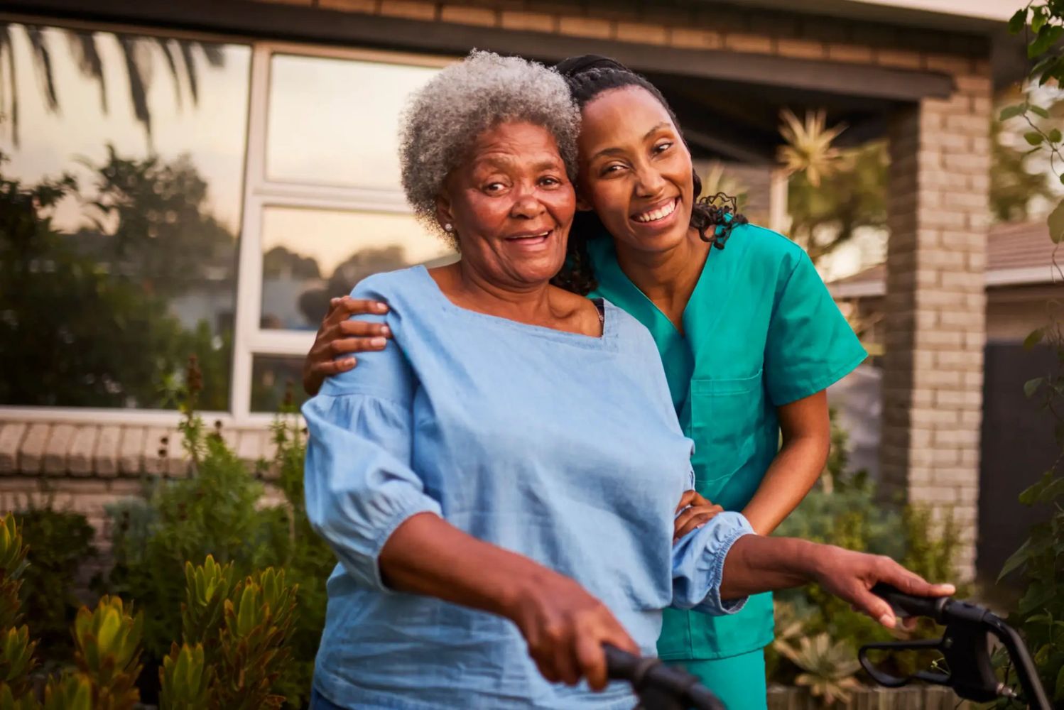 Caregiver hugging smiling elderly woman.