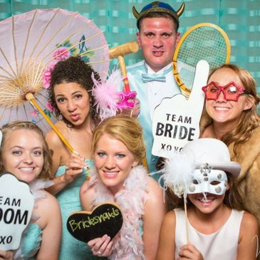 People in a photo booth with silly props.