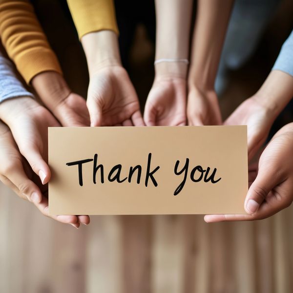 Hands holding a card that says 'Thank you'.