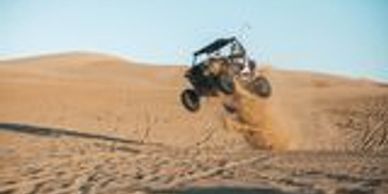 Off-road vehicle flying in the desert sand.