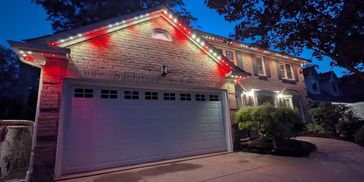 House decorated with red and white holiday lights at night.