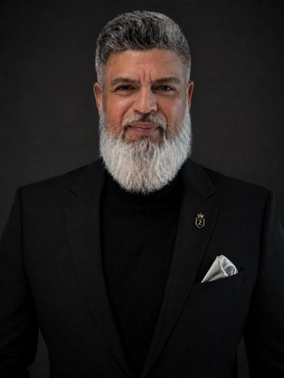Confident mature man with gray beard in elegant black suit.