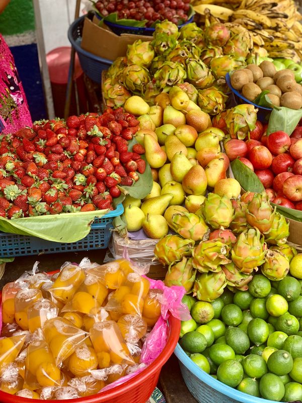 A vibrant market stall with various fresh fruits and juice packs.