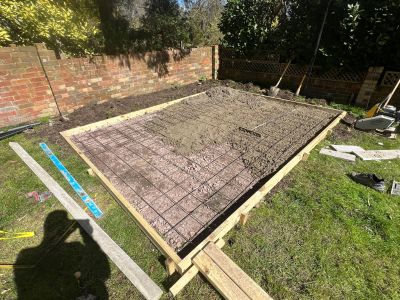 Concrete being poured over a wire mesh foundation in a backyard.