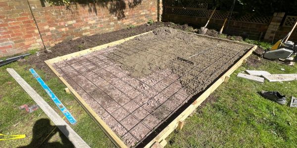 Concrete foundation being prepared with rebar grid in a backyard.