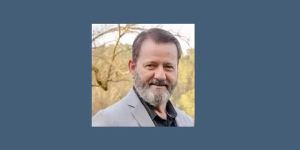 Middle-aged man with a beard smiling outdoors.