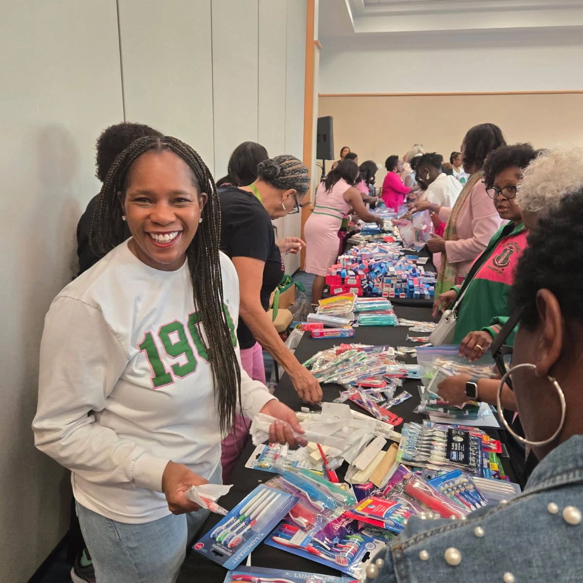 Smiling woman distributing dental care supplies at a community event.