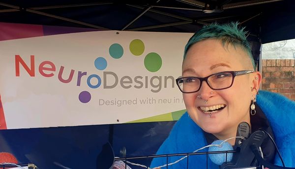Person smiling at a booth with a 'NeuroDesign' banner.