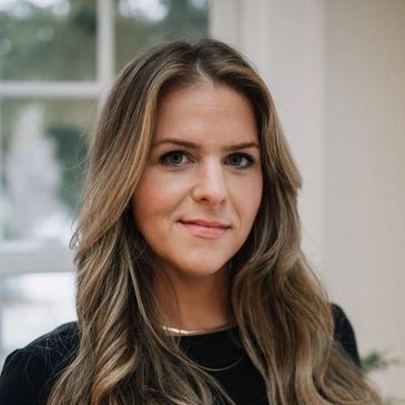 Portrait of a confident woman with long wavy hair and a soft smile.