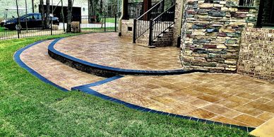 Curved stone patio with blue trim and steps leading up to a house.