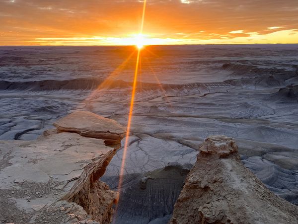 Sunset over a rocky desert canyon with dramatic clouds.