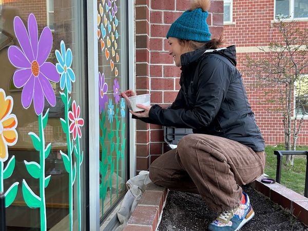 Artist painting flowers on school window