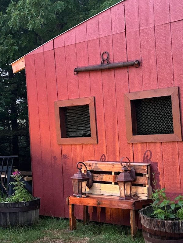 Rustic wooden bench with lanterns in front of a red barn wall.