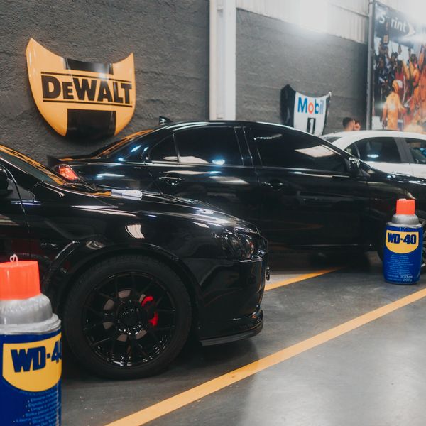 Black sports cars parked indoors near WD-40 cans and a DeWalt sign.