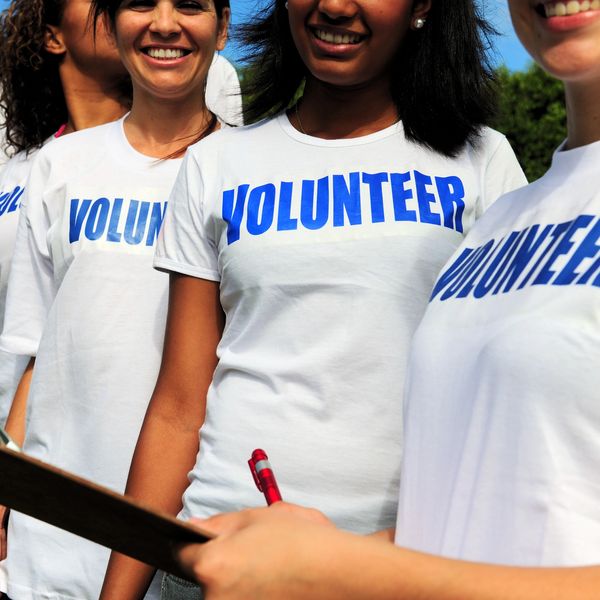 Smiling volunteers wearing white shirts with 'VOLUNTEER' text.