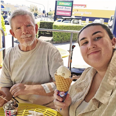 Two people enjoying ice cream outdoors on a sunny day.