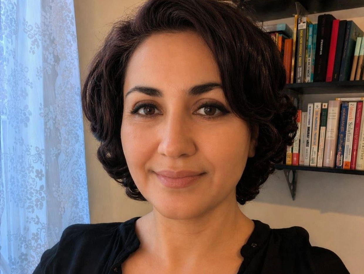 Woman with short curly hair smiling.