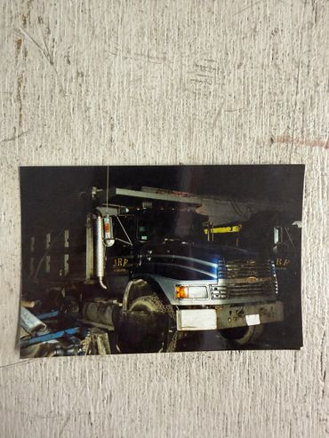 A dark photo of a JRF truck with a blue stripe, parked indoors.