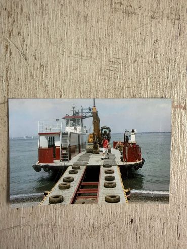 A barge with construction equipment docked at a shoreline.