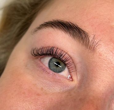 Close-up of an eye with long, curled eyelashes and a well-groomed eyebrow.