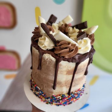 Vanilla and chocolate cake with chocolate drip, rainbow sprinkles, and chocolate pieces.