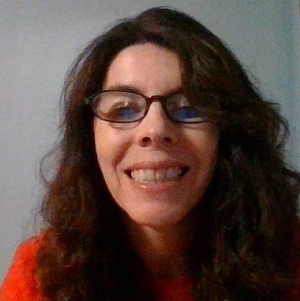 Woman with glasses smiling warmly at the camera.