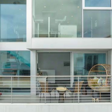 Blue Wave Beach House Manhattan Beach, CA. Modern balcony with chairs and a wicker egg chair.
