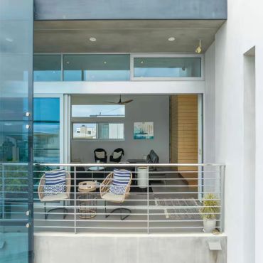 Blue Wave Beach House 3rd Floor Balcony. Modern balcony with seating and a view inside the living room.