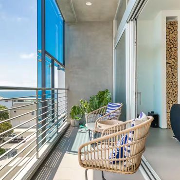 Blue Wave Beach House, Manhattan Beach, CA, Vacation luxury Rental. Modern balcony with wicker chairs and plants overlooking a coastal neighborhood. Ocean Views