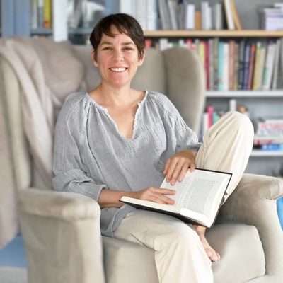 Mujer sonriente leyendo en un sillón cómodo.