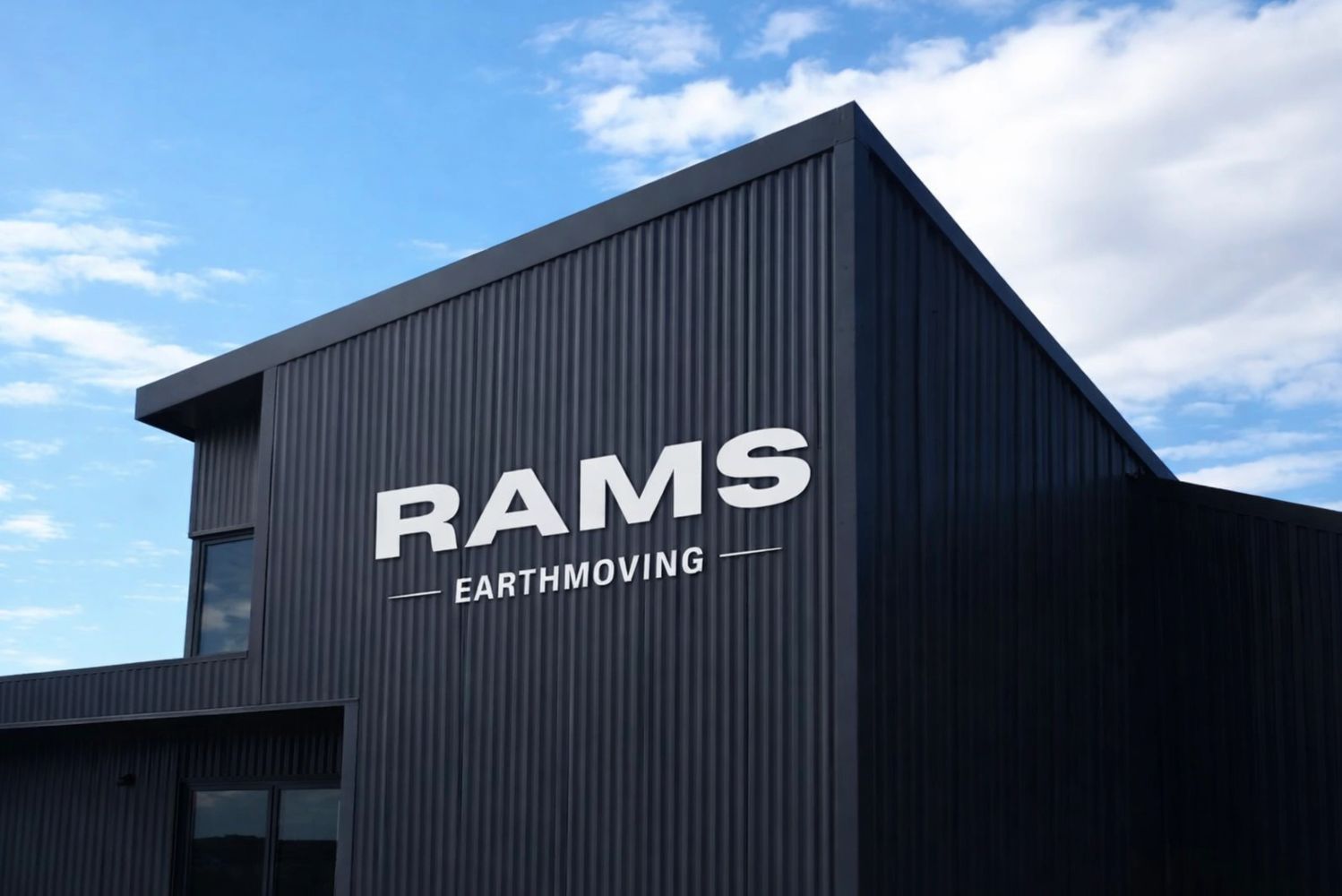 Black corrugated building with RAMS Earthmoving sign under a blue sky.