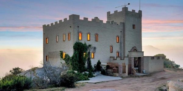 A castle-like building with warm glowing windows at sunset.