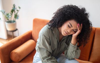 Woman looking stressed on an orange couch.
