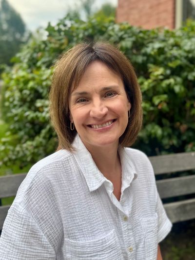 Woman smiling while sitting on outdoor bench.