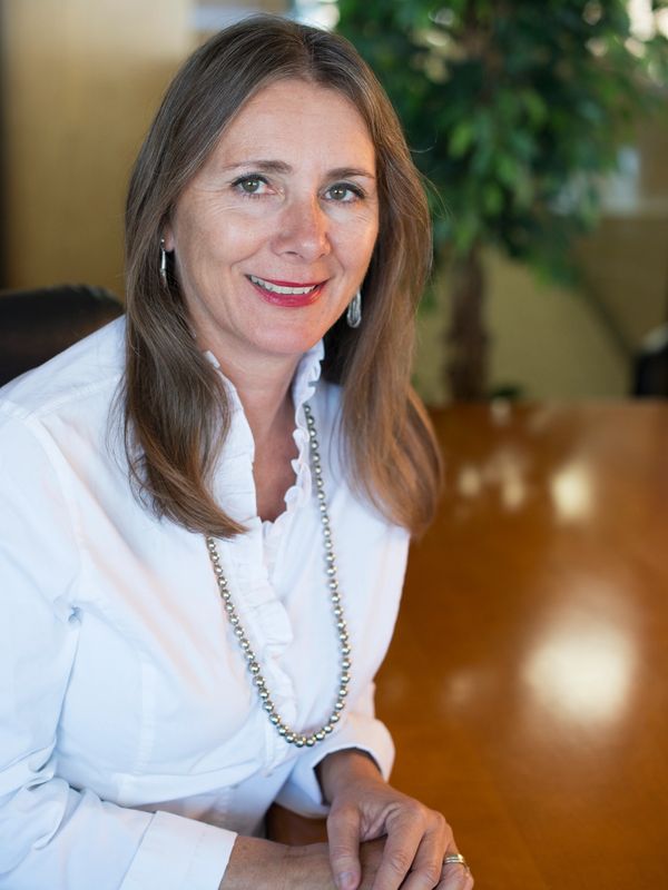 Professional woman in white blouse sitting at a conference table.