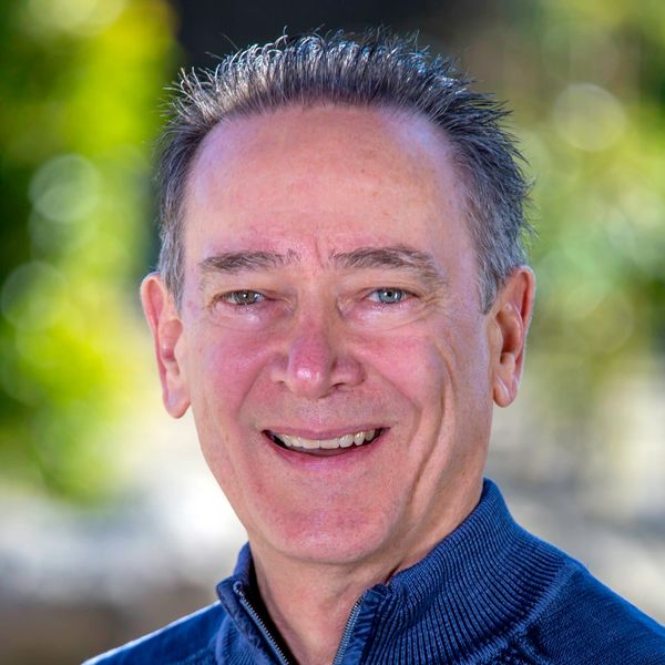 Smiling middle-aged man with short hair in a blue sweater.