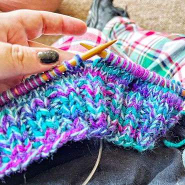 a knit hat on the knitting needles during creation