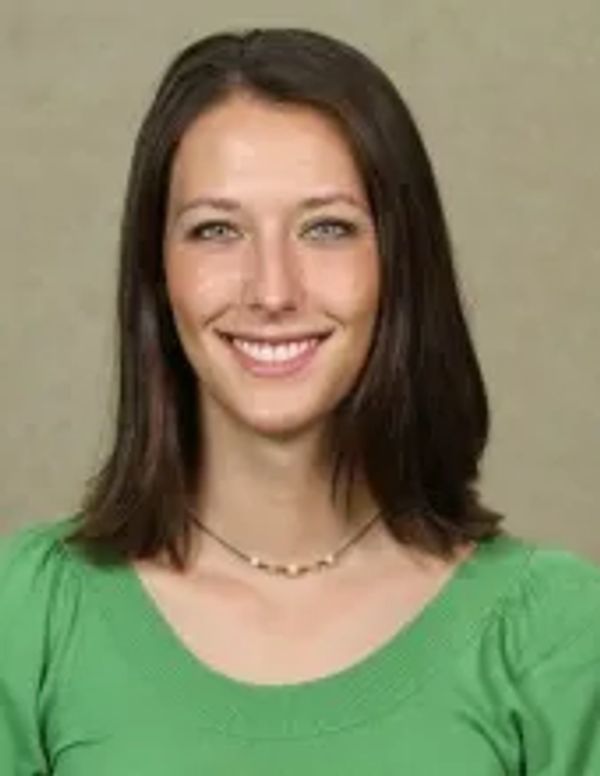 Smiling young woman with straight brown hair wearing a green top.
